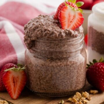 Creamy Chocolate Coconut Chia Pudding topped with fresh strawberries in a jar, slightly overflowing