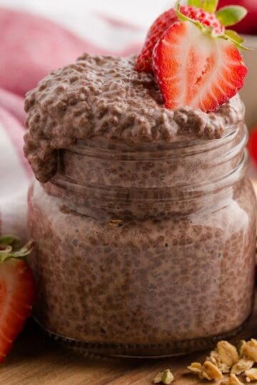 Creamy Chocolate Coconut Chia Pudding topped with fresh strawberries in a jar, slightly overflowing